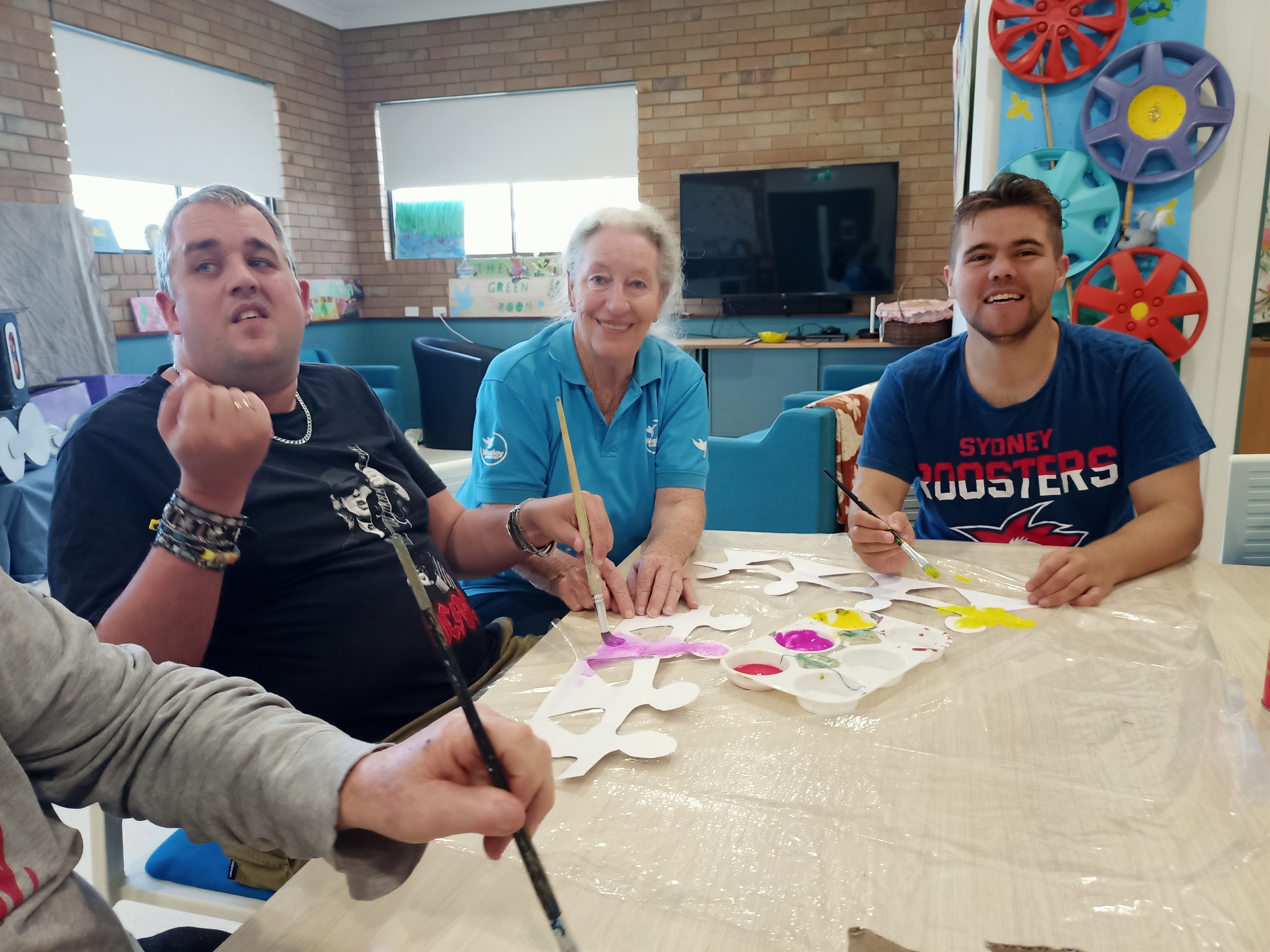 3 people at a table, laughing, painting. 3 people at a table, laughing, painting.