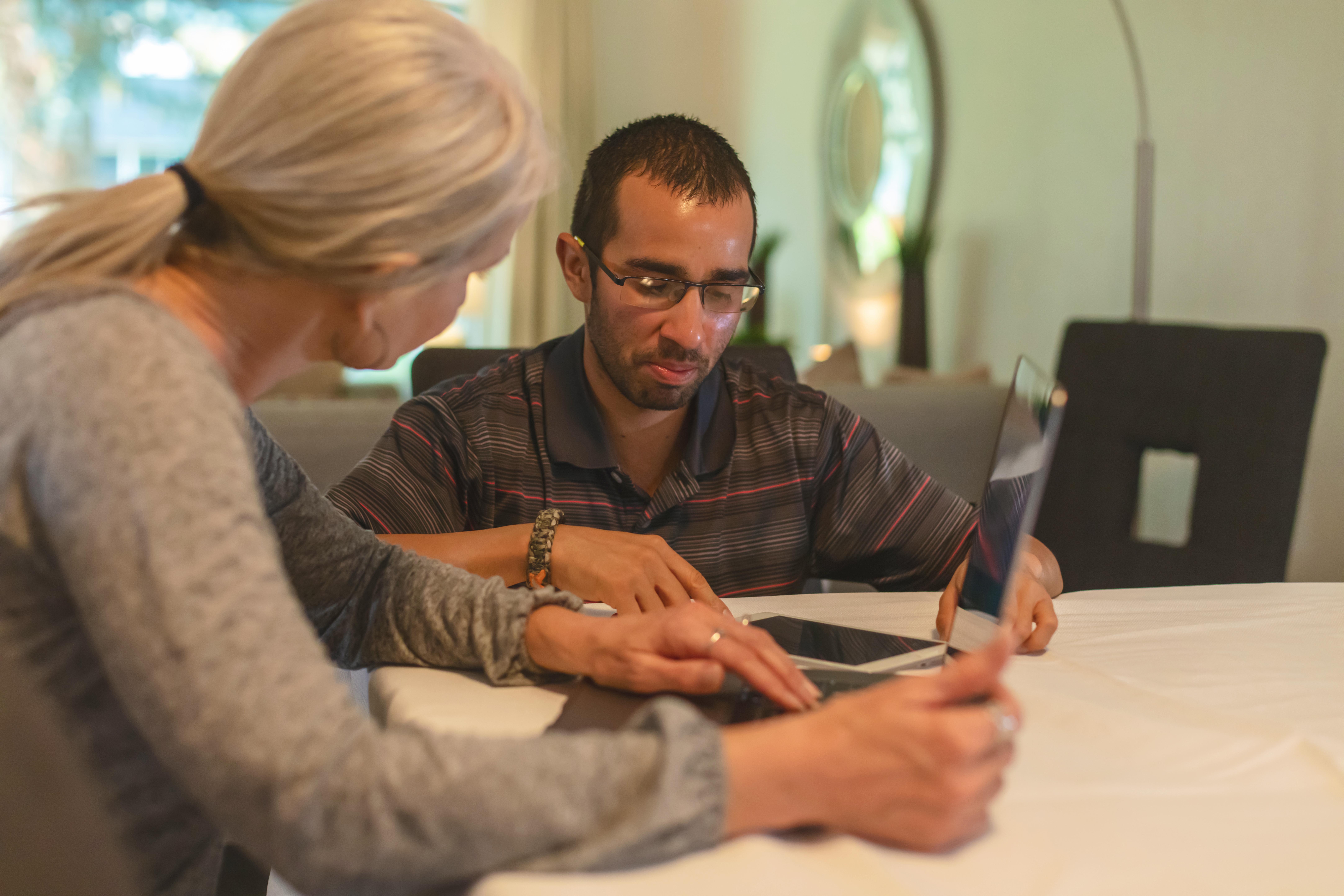 Man and a woman sitting at a table, both looking at a laptop. Man and a woman sitting at a table, both looking at a laptop.